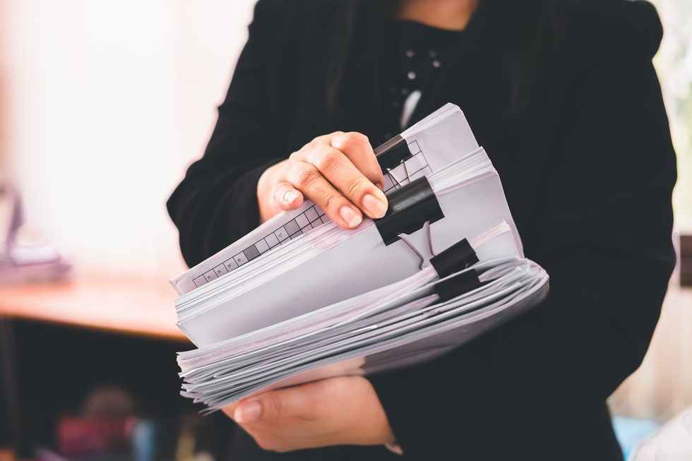 Woman Holding Stack of Paper Documents